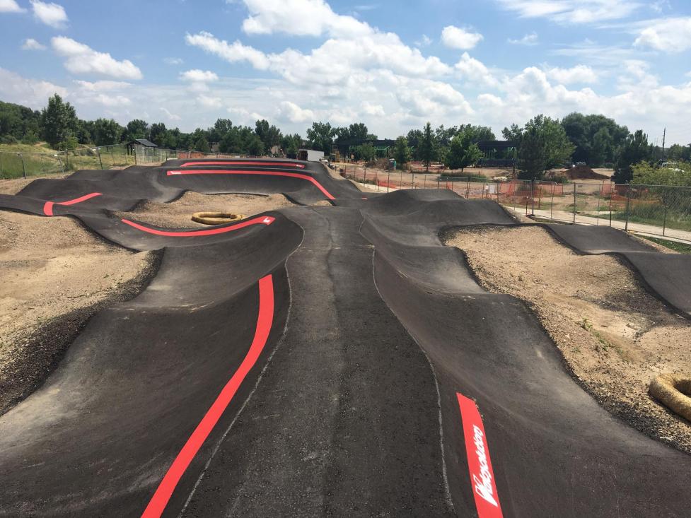 The completed pump track at Valmont City Park, black molded asphalt surrounded by dirt awaiting grass to seed.
