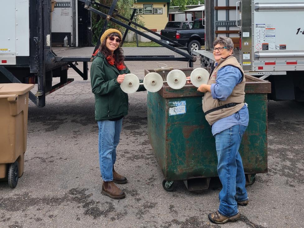Two city staff members hold up an old light fixture that will be recycled.