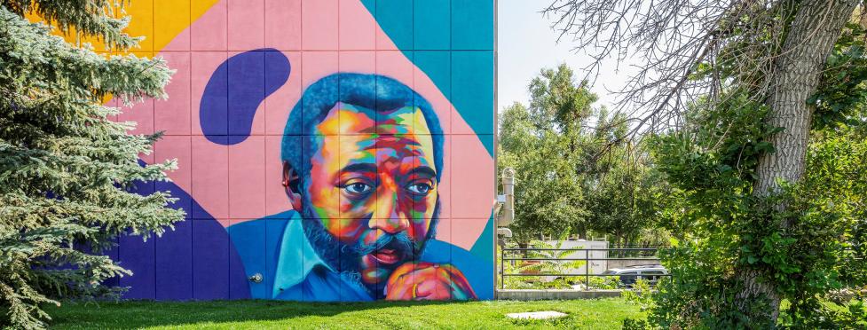 Colorful mural on the side of a city building. The mural depicts Penfield Tate II, Boulder's first and only Black mayor.