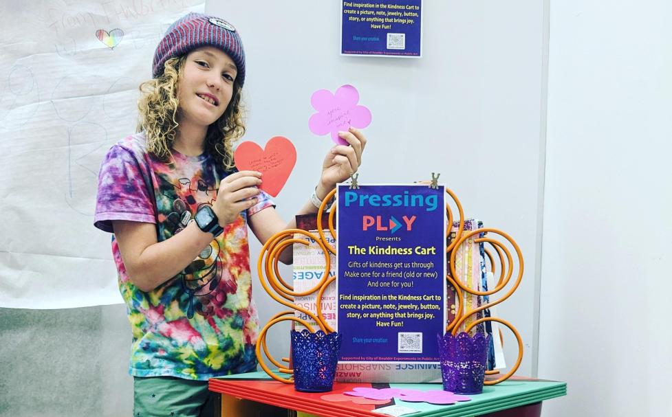 Child interacting with the "Kindness Cart" interactive art piece.