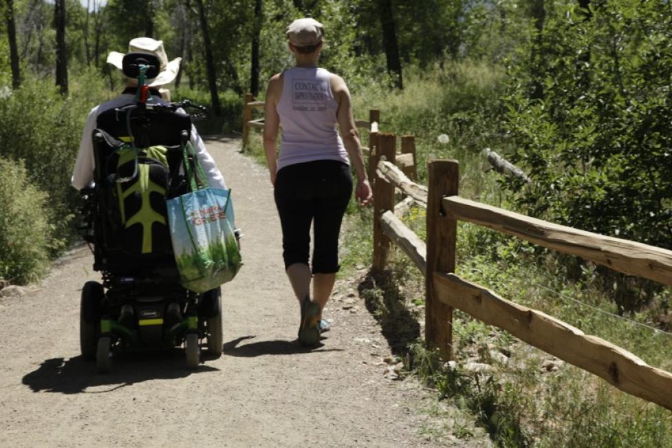 A person walking with a person using a wheelchair on an accessible, gravel trail