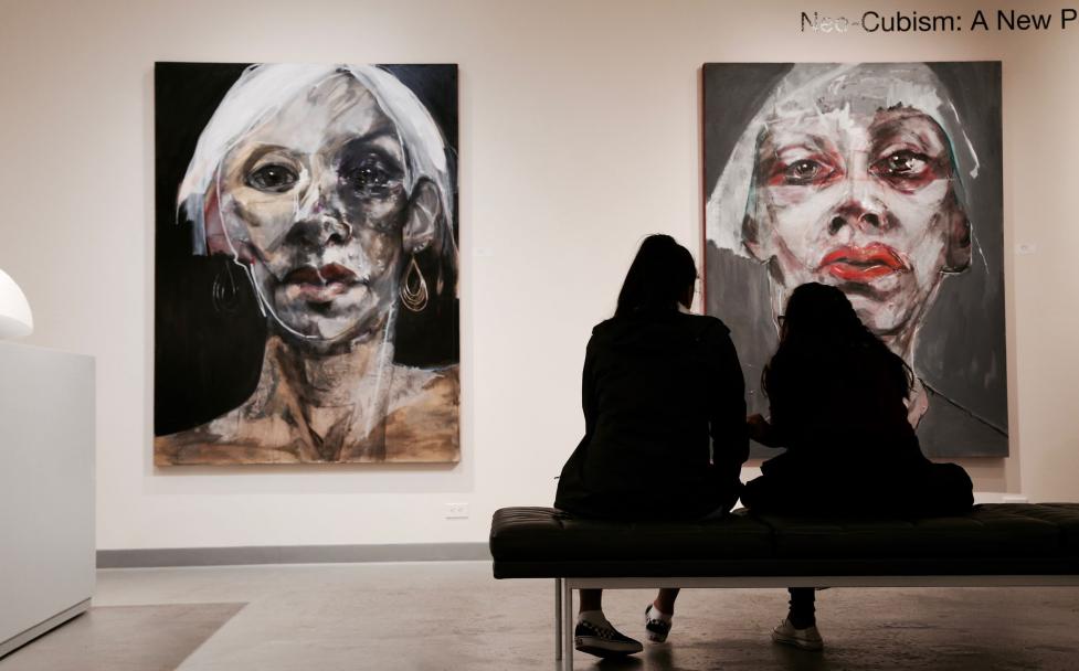 Silhouette of two people looking at paintings in an art gallery