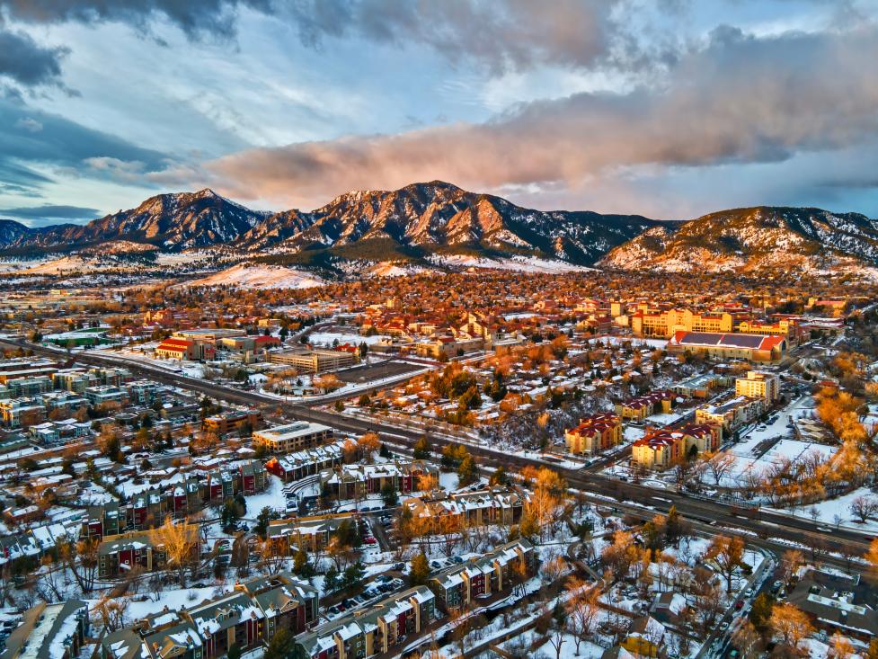 Aerial view of City of Boulder toward the Flatirons at dusk with a dusting of snow