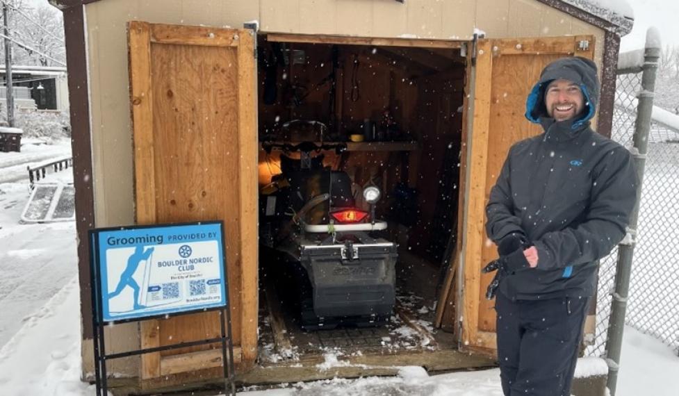 volunteer cross country ski groomer in front of the snowmobile trailer