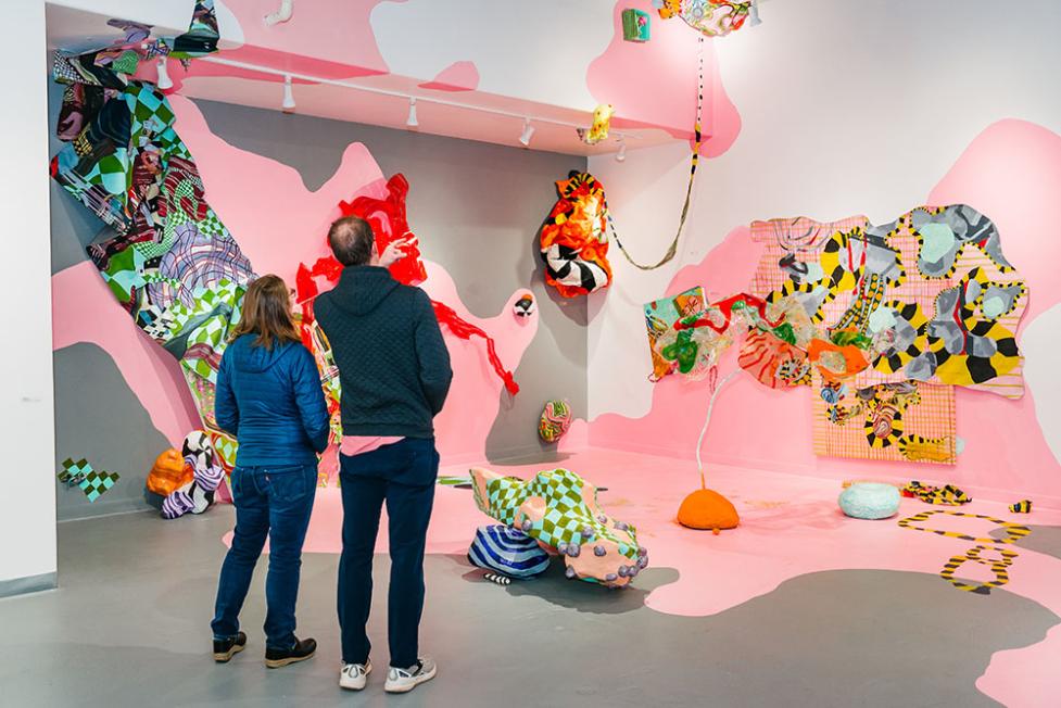 Attendees of a gallery admiring abstract work on a wall