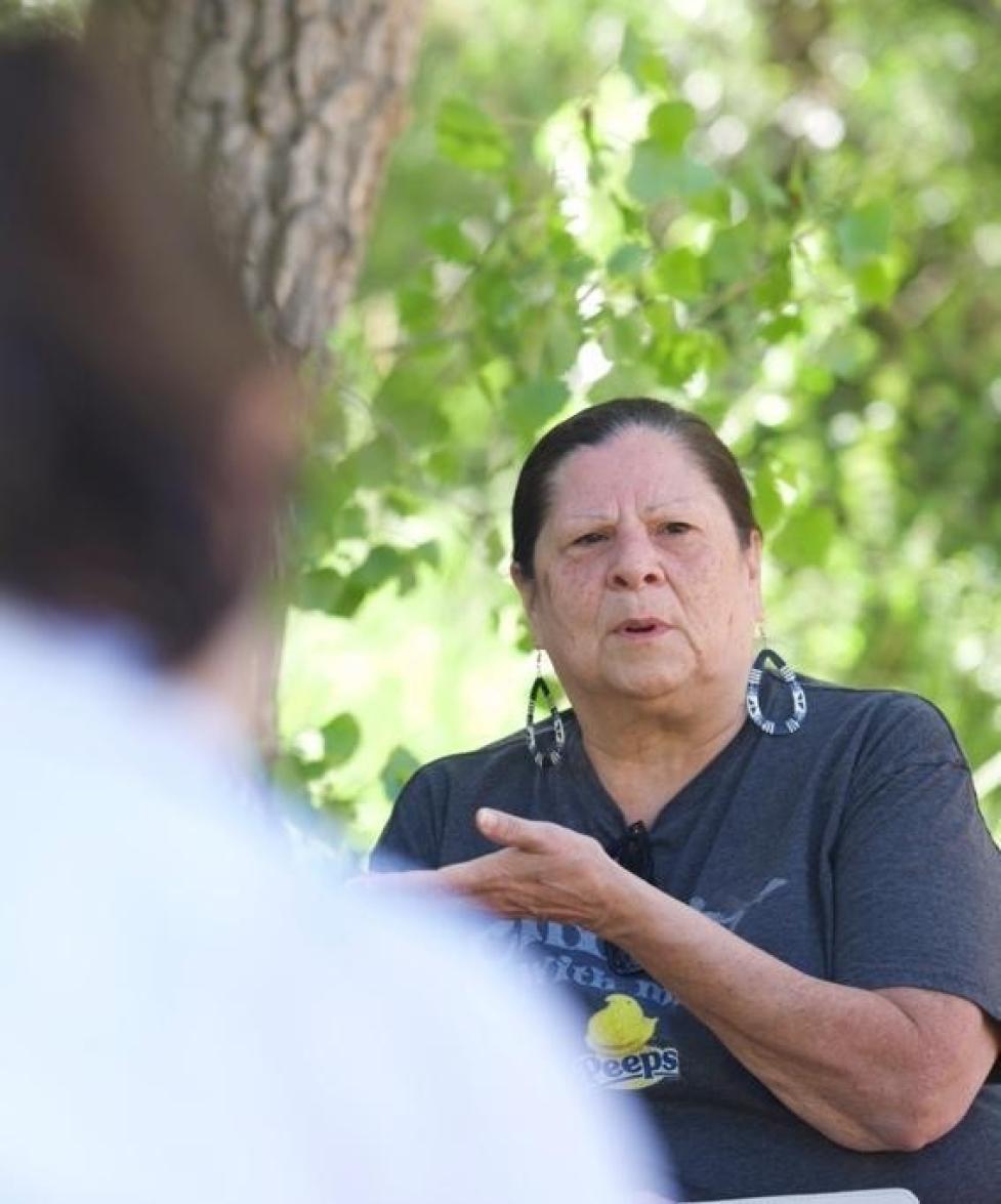 Portrait of Ms. Martha Only A Chief speaking while seated in a wooded area.