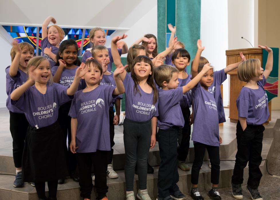 Children waving and smiling who are part of a children's chorale