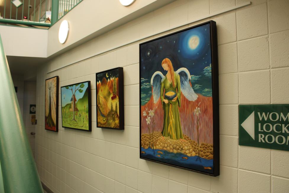 four oil paintings displayed at South Boulder Recreation Center next to a Women's Locker Room sign