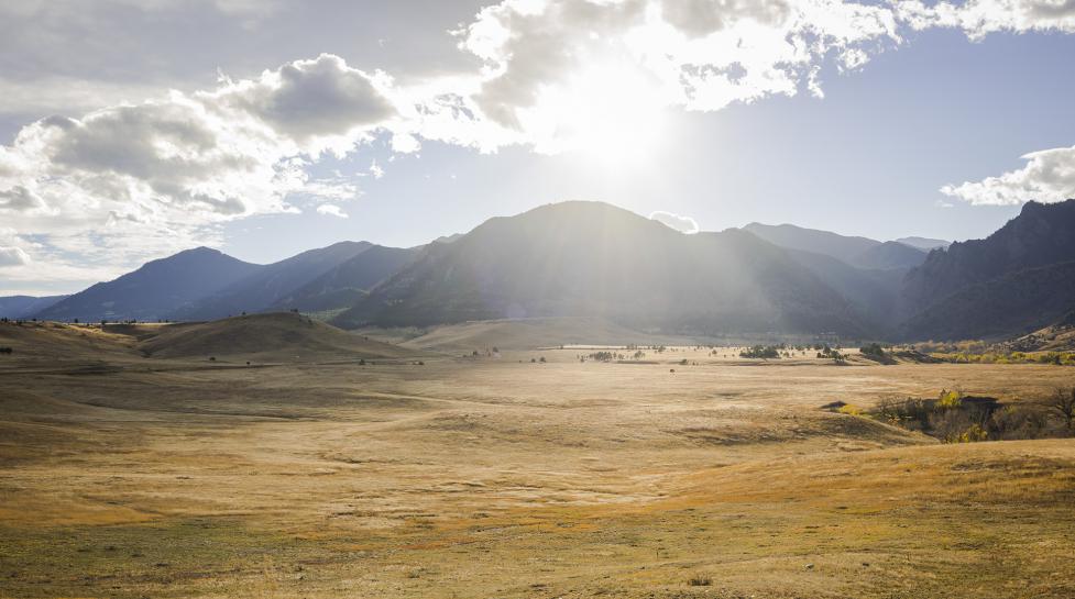 Open space south of Boulder. Sun glare peers out of the clouds above Boulder's mountain backdrop