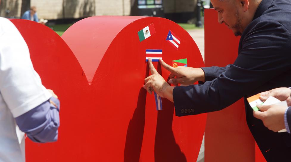 Man putting flag sticker on the heart of an 'I [heart] Boulder' sign