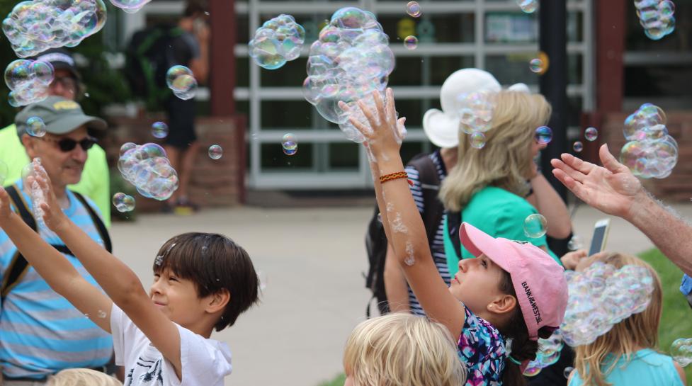 Children reaching up to grab bubbles
