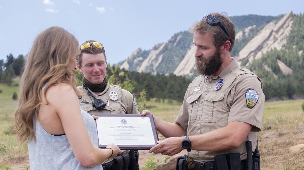OSMP Rangers give an award to a citizen for helping an injured climber