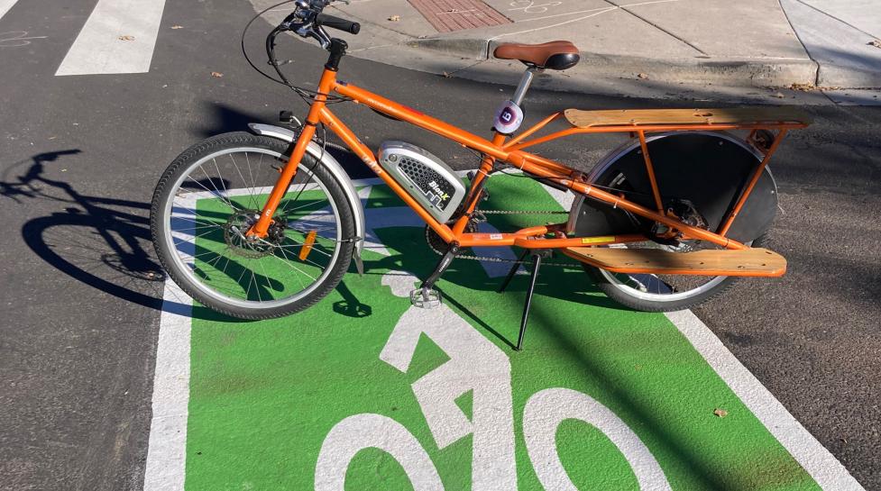 A bright orange bike on a two-stage left-turn queue box