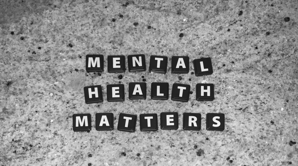 Black letter tiles on a granite background that say "Mental Health Matters"