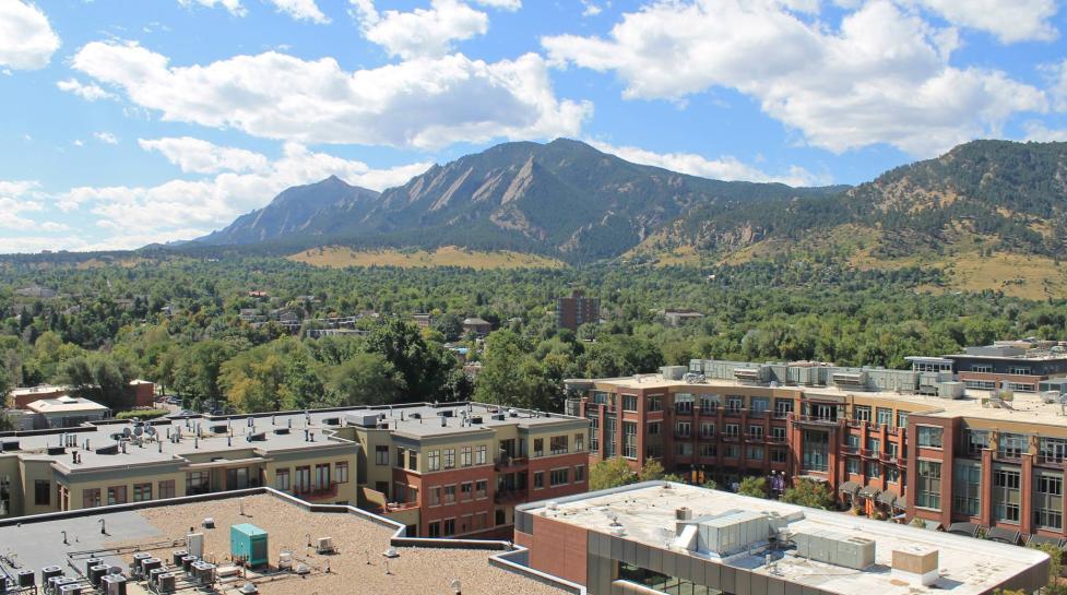 Photo of city buildings with Boulder's mountains behind them.