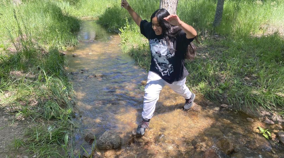 Teenager jumping over the creek at the future park on Violet Avenue