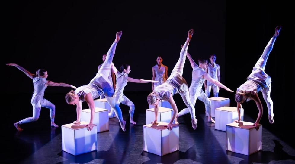 Dancers performing a symmetrical piece on stage.
