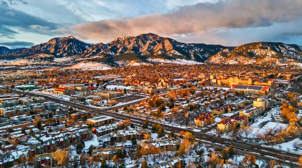 Drone view of University of Colorado, Boulder and the Flatirons at sunrise in the winter snow.