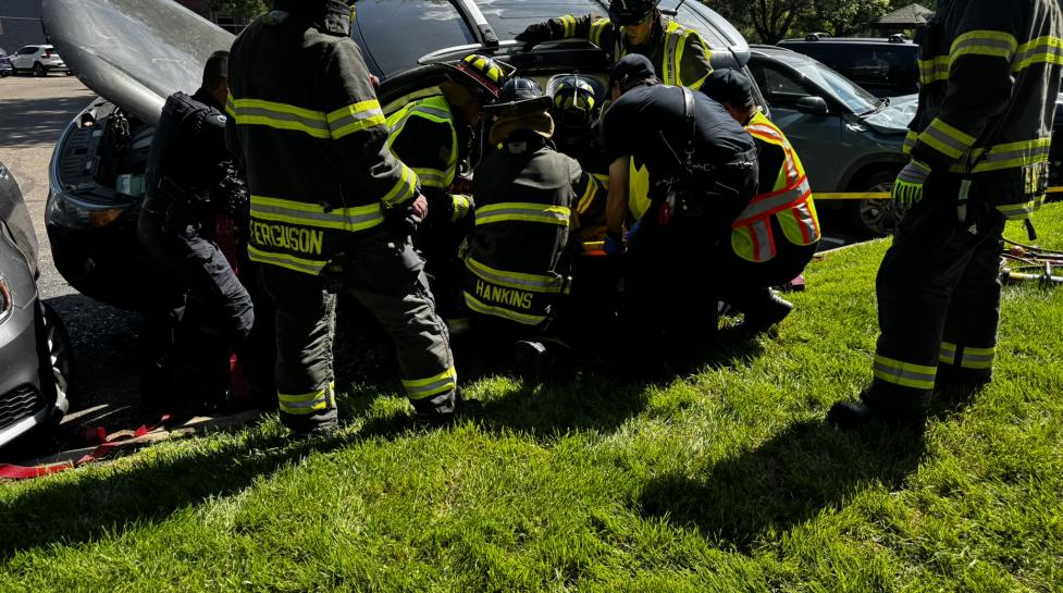 Boulder Fire-Rescue firefighters gather around a vehicle in a crash. Firefighters wear black and yellow bunker gear and work to stabilize the vehicle for a rescue