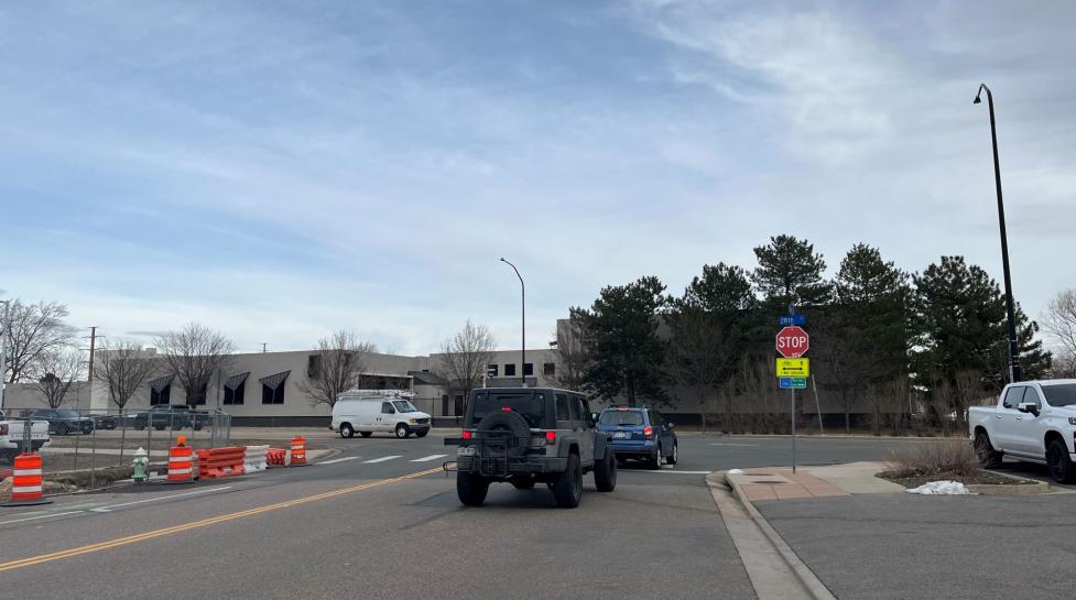 Cars at Pine/28th street crosswalk behind stop sign and signage for two-way bike/walk travel on the sidewalk.