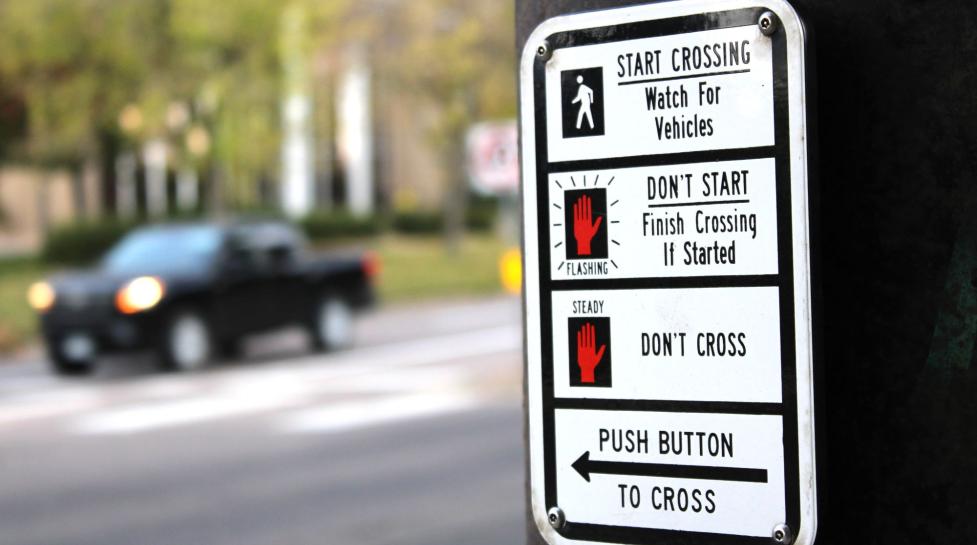 Crosswalk sign with instructions to push button