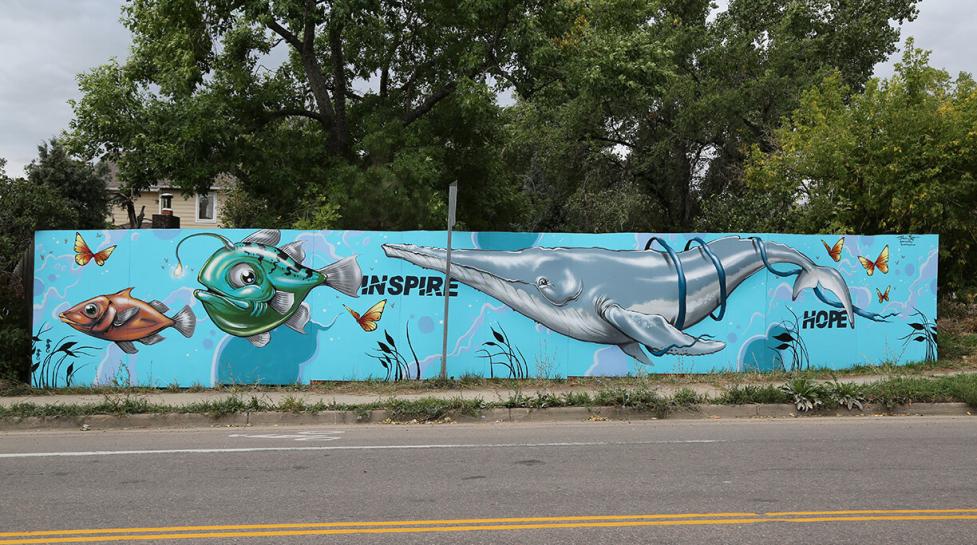 Mural on a neighborhood fence with fish and the words 'inspire' and 'hope'