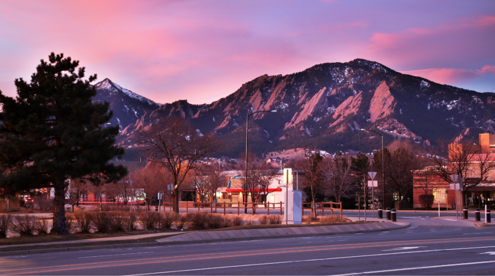 city of Boulder with flatirons and city street at sunset