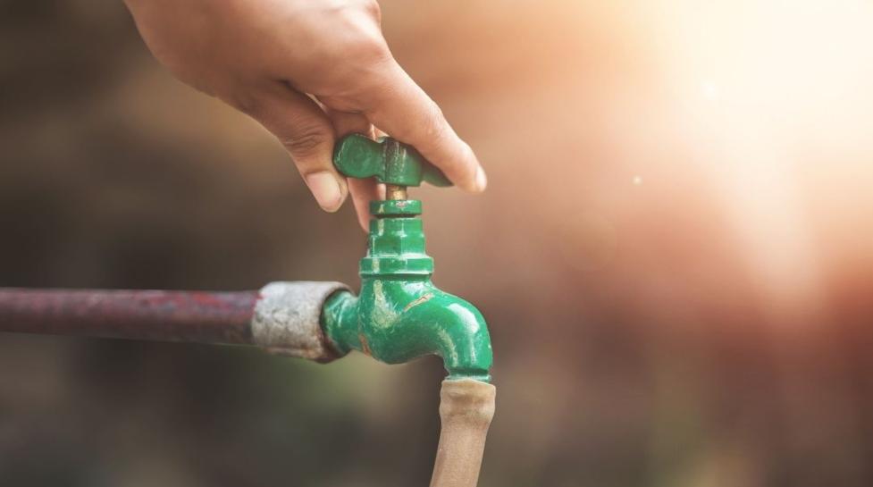 Hand turning off water spigot