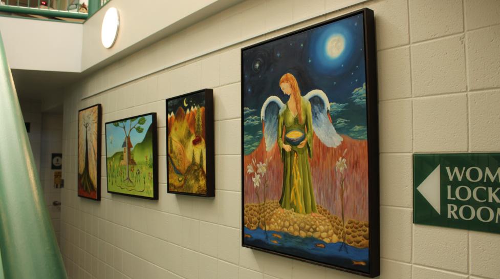 four oil paintings displayed at South Boulder Recreation Center next to a Women's Locker Room sign