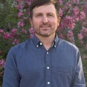 man smiling in front of flowers