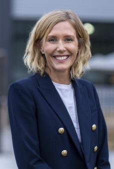 Women with blonde hair wearing a navy suit jacket and smiling