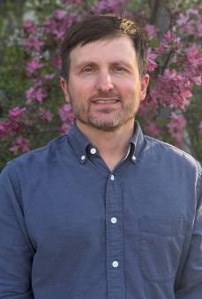 man smiling in front of flowers