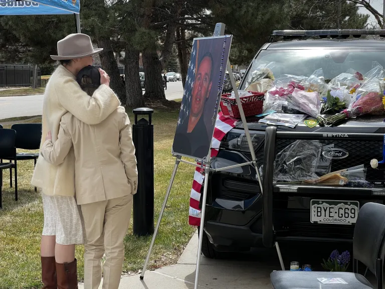 Two people embracing in front of Officer Talley memorial at Boulder Police Department