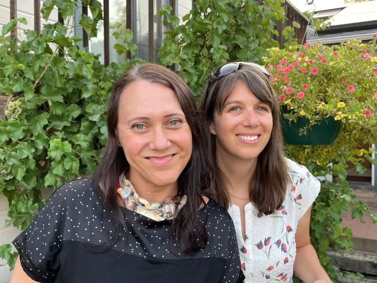 Two people posing for photo in front of garden