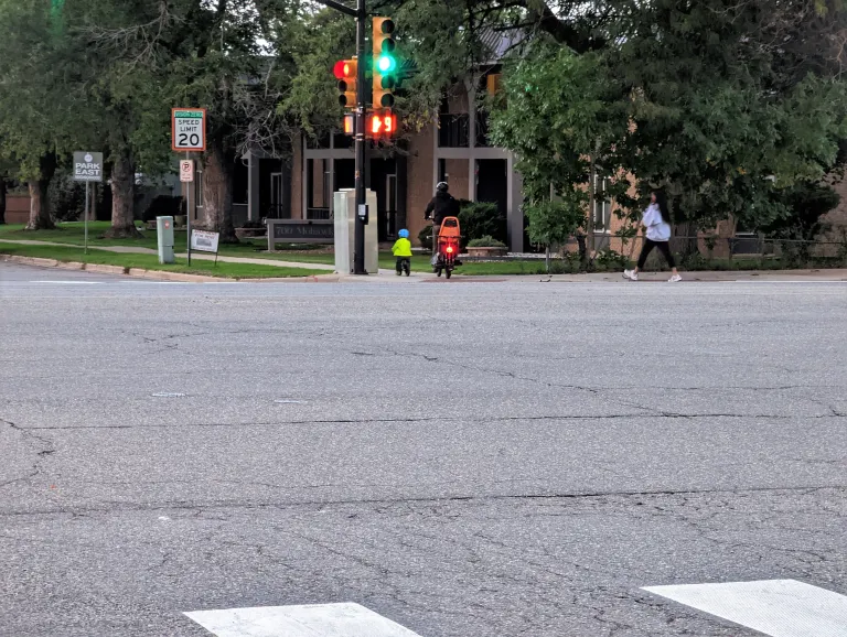 People biking across the road. There is no marked crosswalk where they cross.