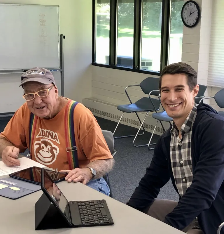 An older adult services volunteer helping a community member with a tablet