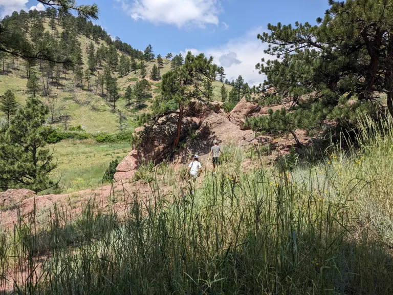 Hikers on the Red Rocks Spur Trail with Anemone Hill in background