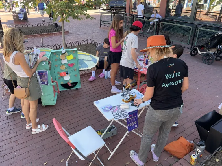 Children and adults interacting with an art station.