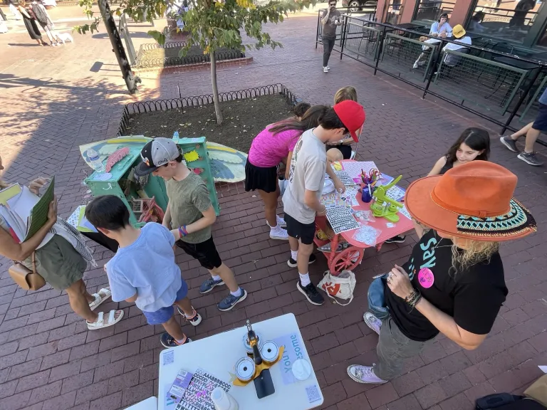 Children and adults interacting with an art station.