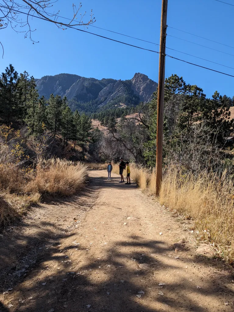 Three hikers on the Enchanted Mesa Trail on a sunny winter day