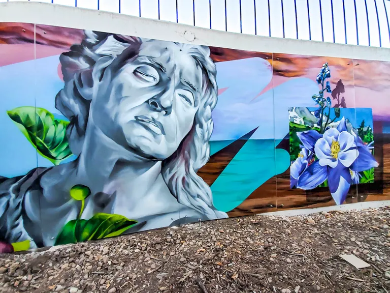 Colorful mural on side of a building featuring a statue bust and flowers
