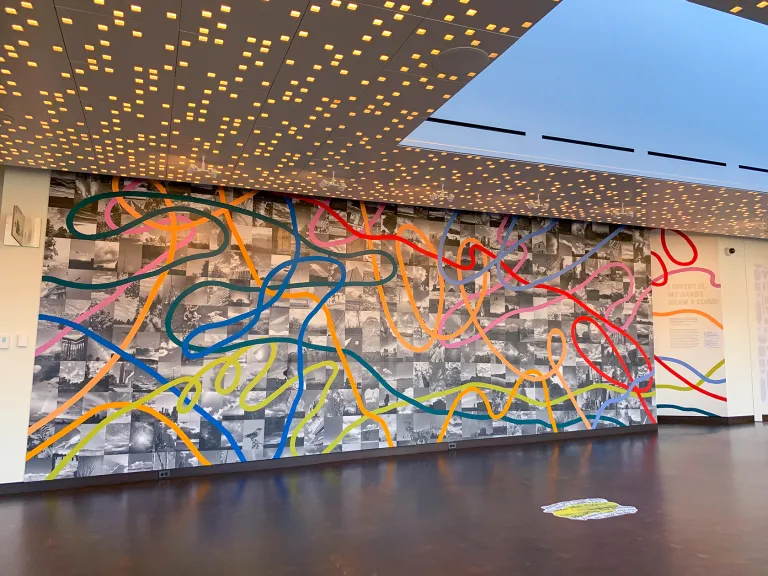 A mural of black and white pictures in the background and bright, squiggly lines in front