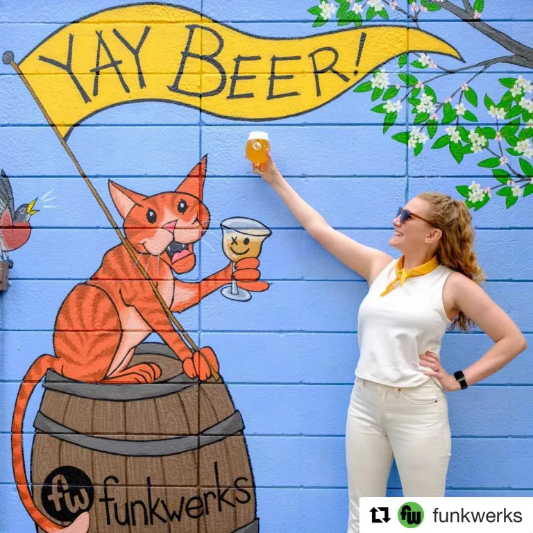 Mural of a fictionalized cat holding a drink with a sign
