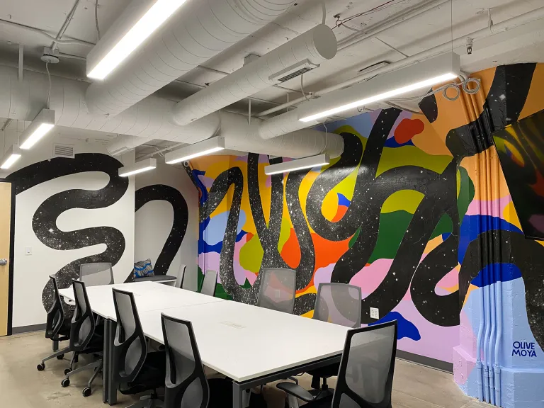 A mural with a colorful collage in the background and thick squiggly lines in the front