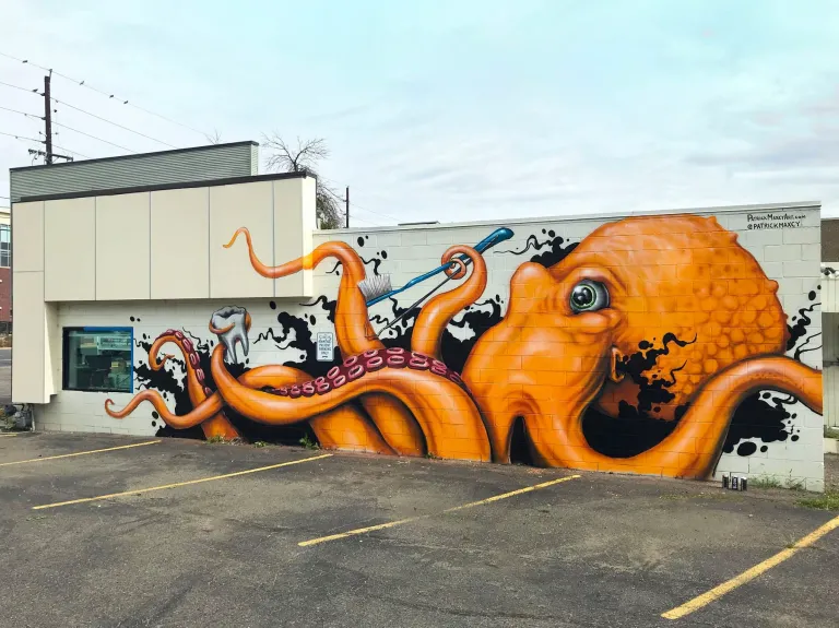 A mural of an orange octopus with a tooth and a toothbrush