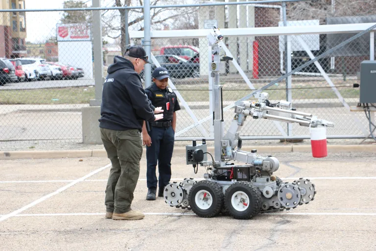 A Boulder Police Officer demonstrating use of an explosives detection robot with a kid in a police uniform