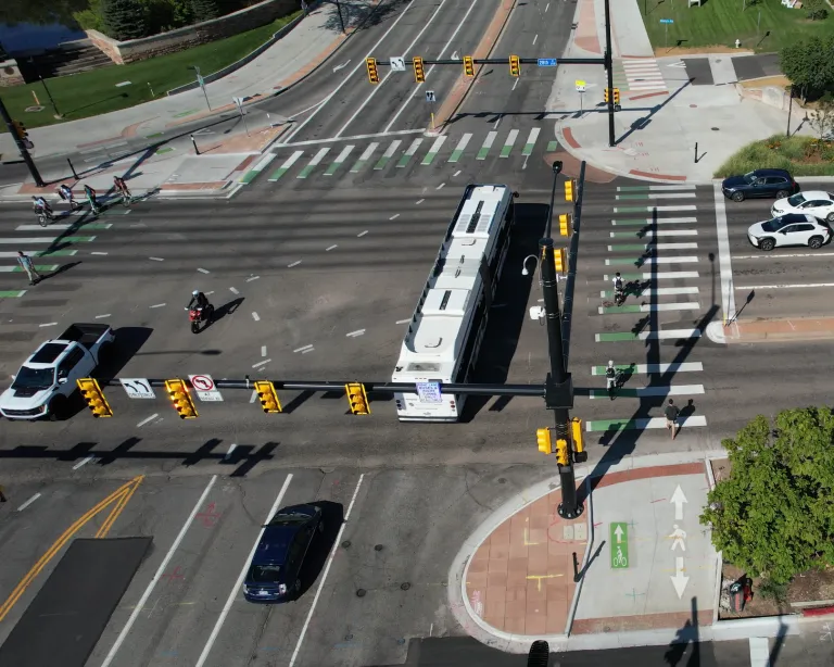 People traveling on the 28th Street and Colorado Avenue protected intersection. There are people biking, walking, taking the bus and driving.