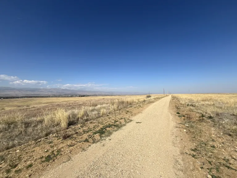 A wide gravel trail through dry, brown prairie in the fall