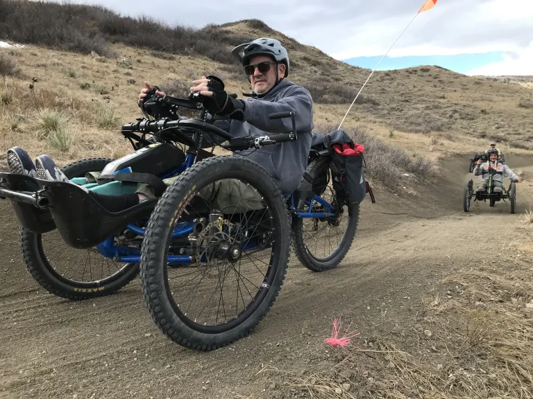 Handcyclists riding on a dirt trail 