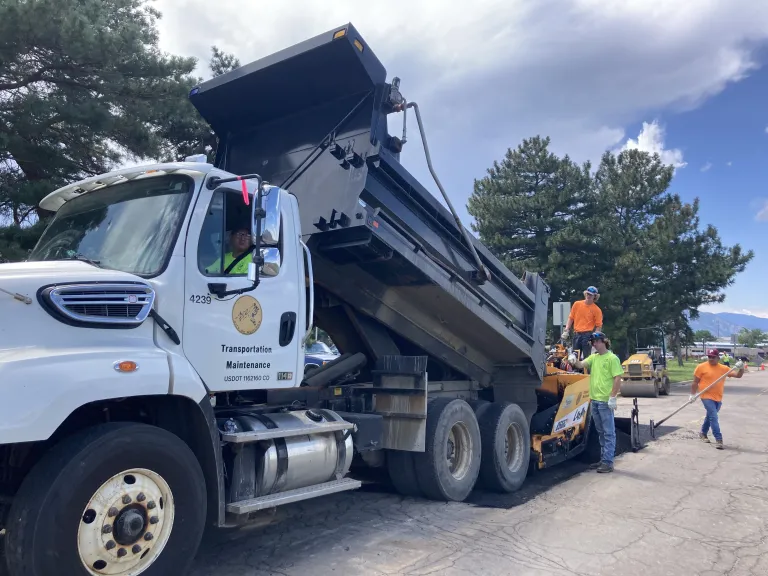 A City of Boulder dump truck unloading materials to repair a pothole.